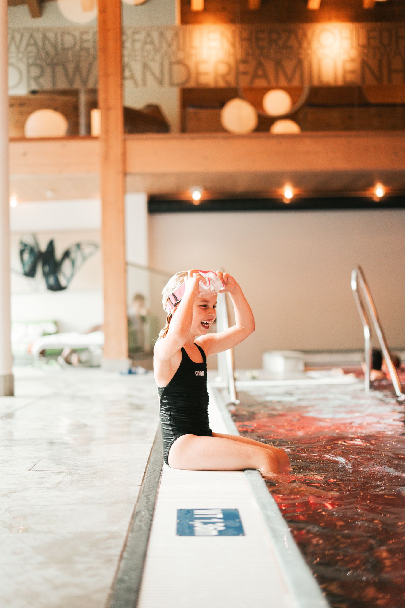 A happy child sits at the poolside in Glemmtalerhof in Hinterglemm.