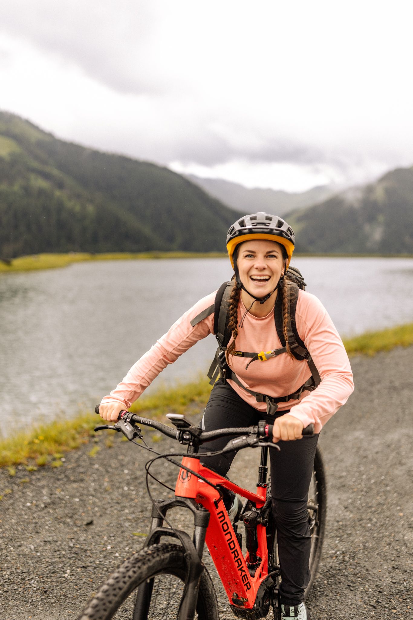 A cheerful cyclist in the Glemmtal by a lake and mountains.