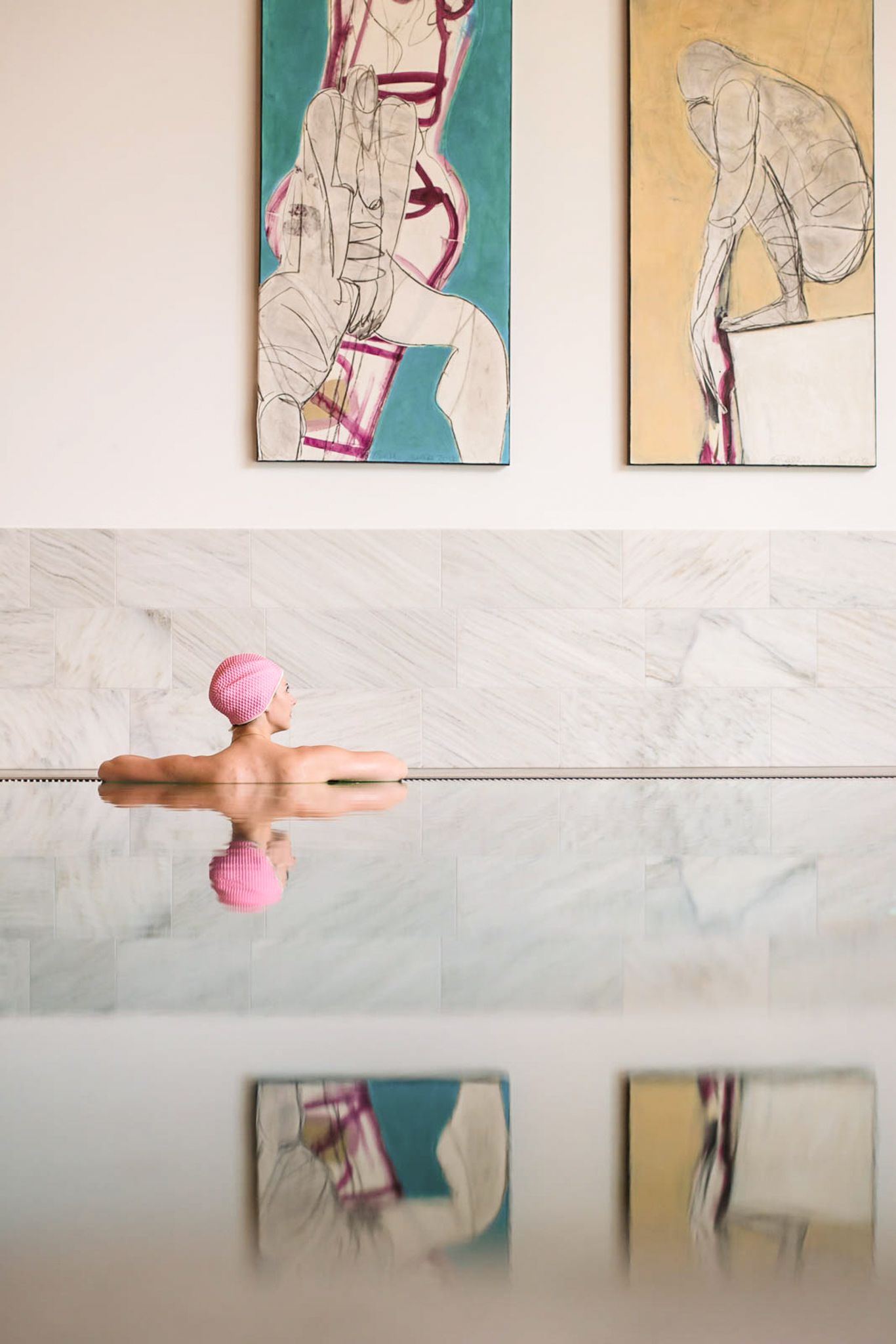 A person relaxes in the water with modern artwork in the background at Glemmtalerhof in Hinterglemm.