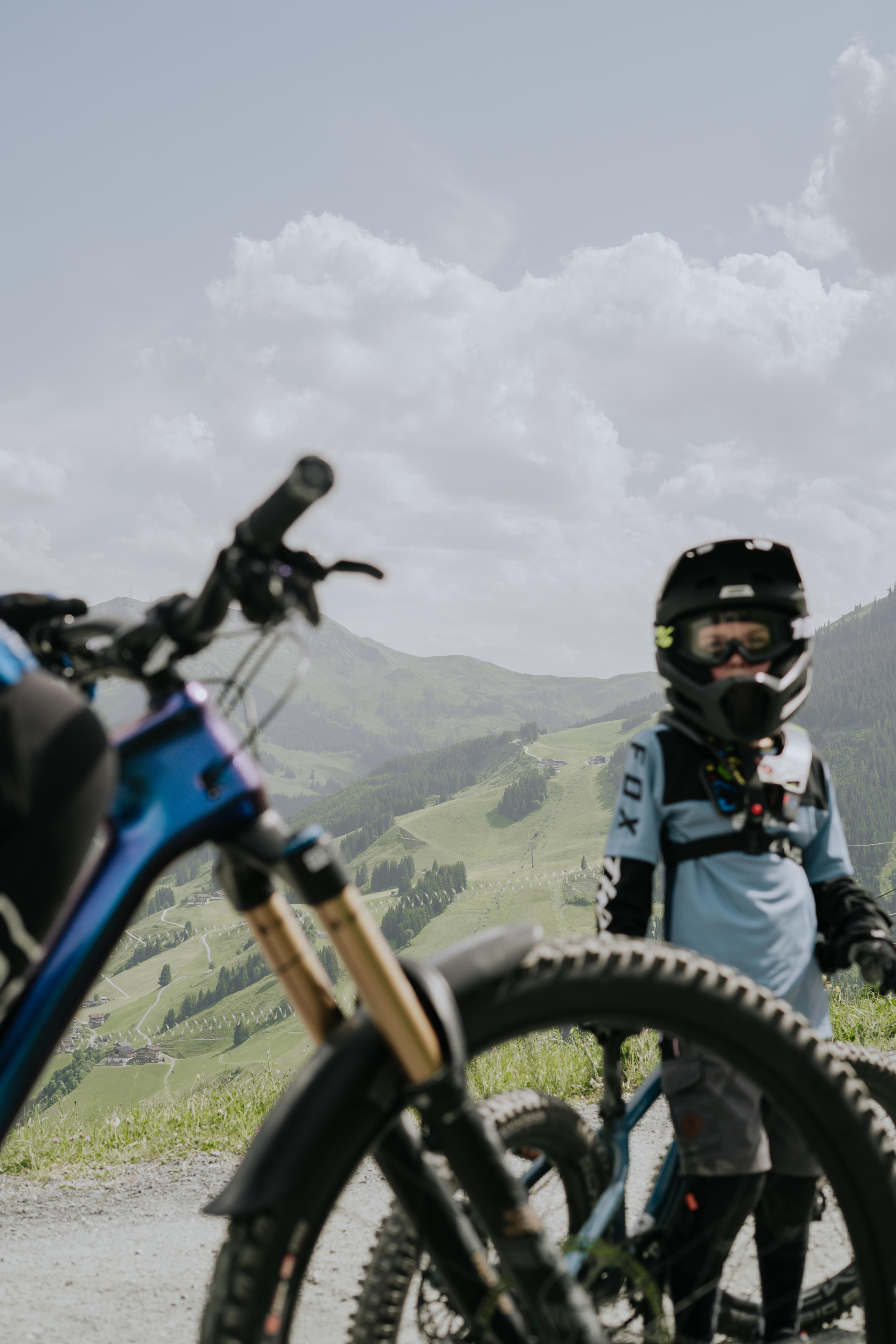 A boy in protective gear stands in Glemmtal with a mountain bike.