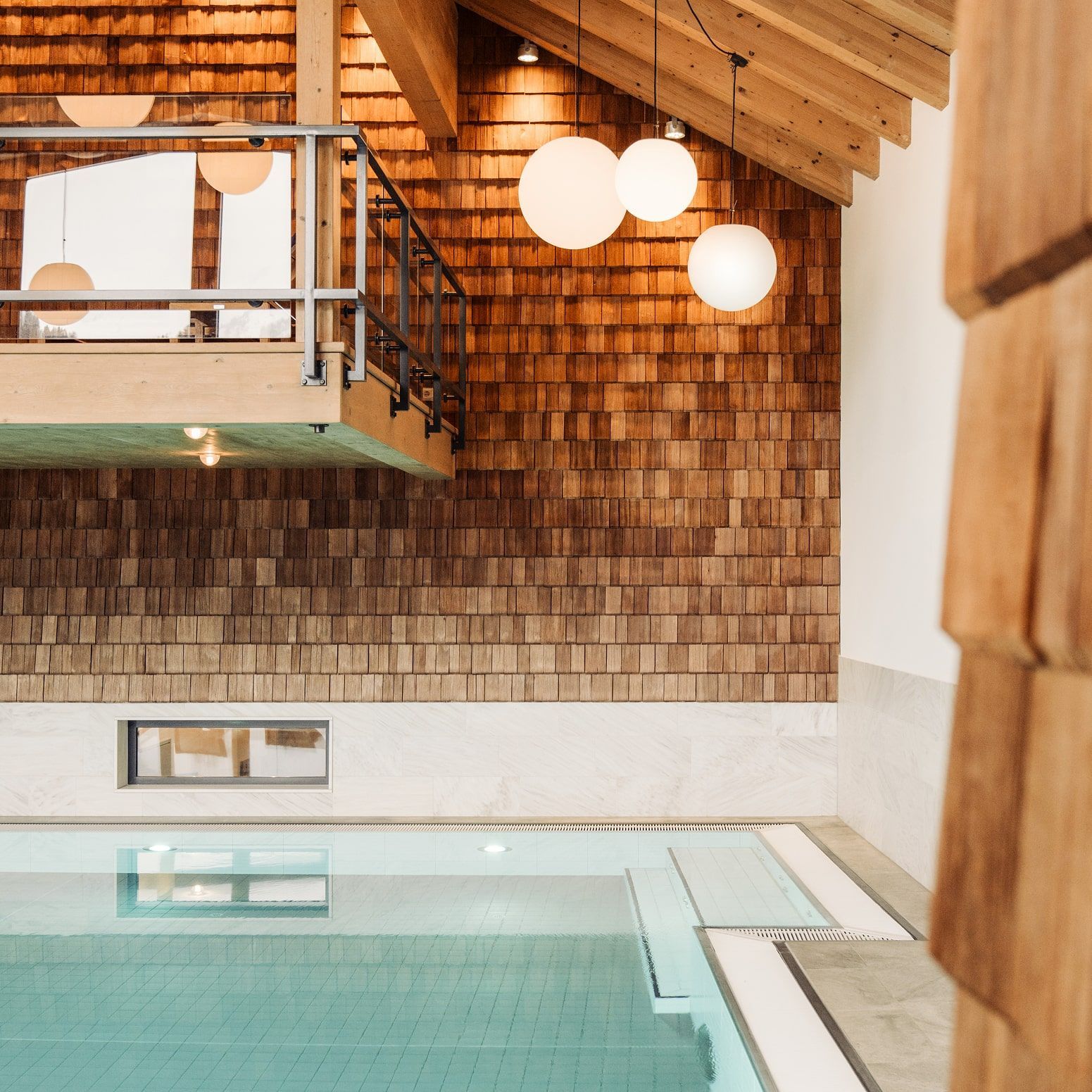 An elegant pool area in the Glemmtalerhof in Hinterglemm with wooden paneling and stylish lights.