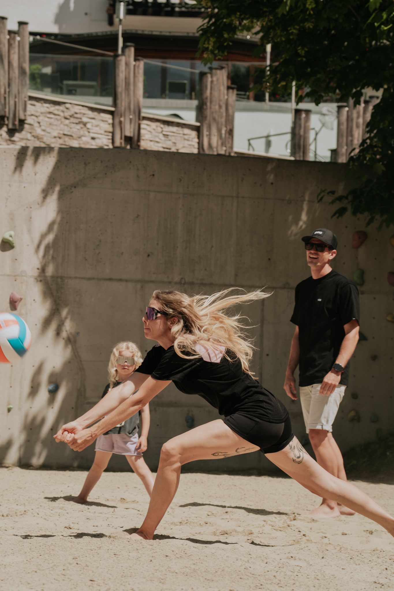 A woman plays volleyball at Glemmtalerhof in Hinterglemm with a child and a man.
